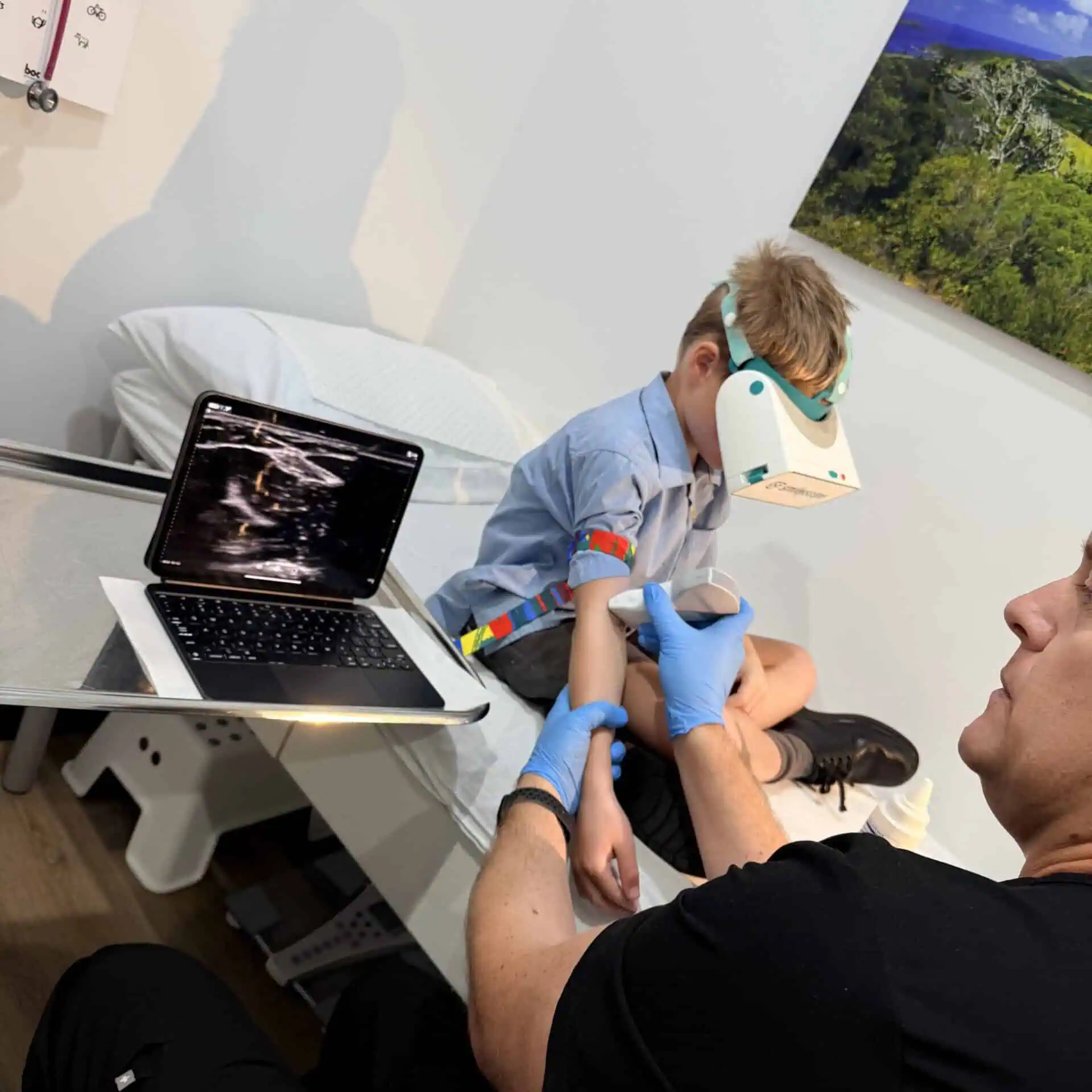 Young boy wearing a VR headset while ultrasound-guided cannulation is being performed at Shire Family Medical